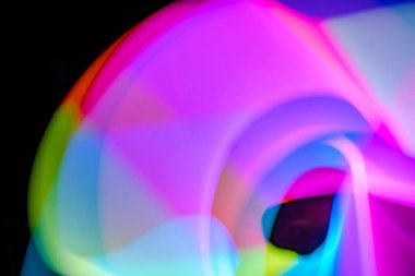 Bulanık efektli ışık resminin soyut görüntüsü. Karanlık arka planda renkli parlak ışıklar kıvrılıyor. Duvar kağıdı, arkaplan veya tasarım ögesi olarak kullanılabilir