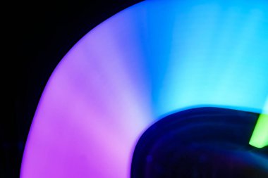 Bulanık efektli ışık resminin soyut görüntüsü. Karanlık arka planda renkli parlak ışıklar kıvrılıyor. Duvar kağıdı, arkaplan veya tasarım ögesi olarak kullanılabilir