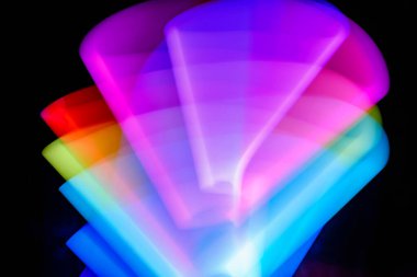 Bulanık efektli ışık resminin soyut görüntüsü. Karanlık arka planda renkli parlak ışıklar kıvrılıyor. Duvar kağıdı, arkaplan veya tasarım ögesi olarak kullanılabilir