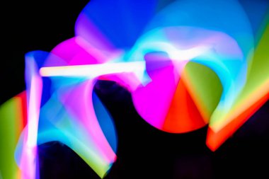 Bulanık efektli ışık resminin soyut görüntüsü. Karanlık arka planda renkli parlak ışıklar kıvrılıyor. Duvar kağıdı, arkaplan veya tasarım ögesi olarak kullanılabilir