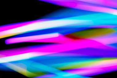 Bulanık efektli ışık resminin soyut görüntüsü. Karanlık arka planda renkli parlak ışıklar kıvrılıyor. Duvar kağıdı, arkaplan veya tasarım ögesi olarak kullanılabilir