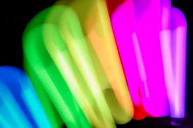 Bulanık efektli ışık resminin soyut görüntüsü. Karanlık arka planda renkli parlak ışıklar kıvrılıyor. Duvar kağıdı, arkaplan veya tasarım ögesi olarak kullanılabilir