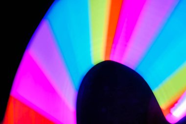 Bulanık efektli ışık resminin soyut görüntüsü. Karanlık arka planda renkli parlak ışıklar kıvrılıyor. Duvar kağıdı, arkaplan veya tasarım ögesi olarak kullanılabilir