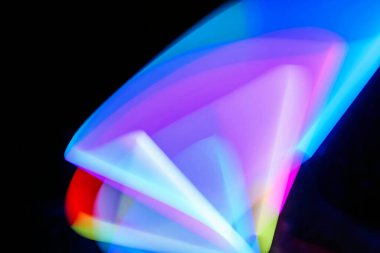 Bulanık efektli ışık resminin soyut görüntüsü. Karanlık arka planda renkli parlak ışıklar kıvrılıyor. Duvar kağıdı, arkaplan veya tasarım ögesi olarak kullanılabilir