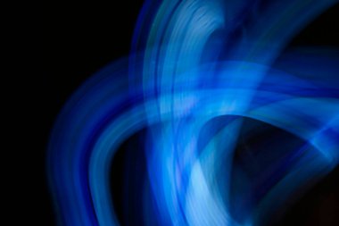 Mavi neon ışığın soyut görüntüsü dairesel ve spiral bir şekilde siyah bir arkaplana karşı. Modern ve gelecek tasarım elementi.