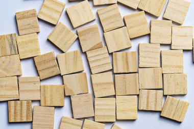 Temiz beyaz bir yüzeye rastgele saçılmış sayısız boş, doğal ahşap karo manzarası. Tahta oyunu kavramları, eğitim veya özel metin eklemek için mükemmel