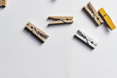 Beyaz bir yüzeye saçılmış küçük doğal, beyaz ve sarı tahta mandallardan oluşan bir derleme metin için yeterli kopya alanı sağlıyor. Çamaşır, zanaat ya da ofis temaları için mükemmel