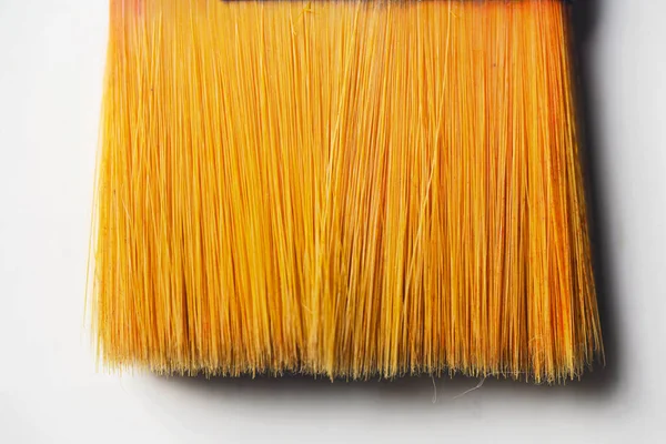Canlı turuncu sentetik kılları ve metal bir dağ gelinciği olan düz bir boya fırçasının makro görüntüsü. Beyaz arka planda izole edilmiş, sanat, zanaat ve yenileme kavramları için mükemmel.
