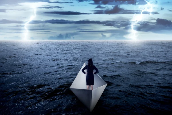 Деловая женщина, стоящая одна на бумажной лодке — стоковое фото