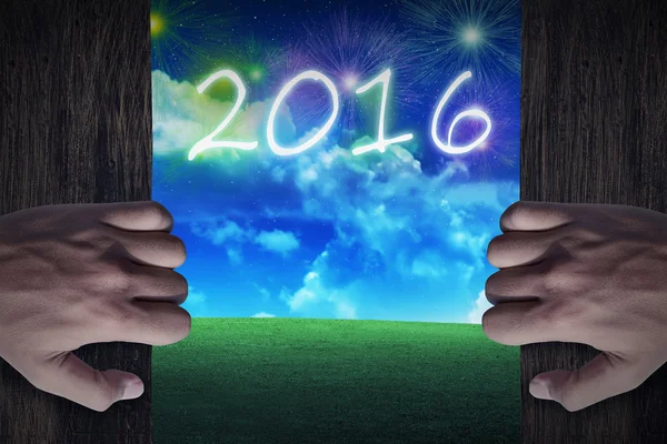 Hands open wooden door to the city that celebrate new year 2016 — Stock Photo, Image