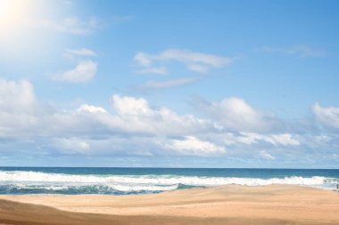 Kumlu, tropikal bir plajın güzel yaz manzarası. Beyaz dalgalar mavi bir okyanusa çarpıyor. Kabarık bulutlu, parlak bir gökyüzünün altında. Seyahat, tatil ve rahatlama temaları için mükemmel