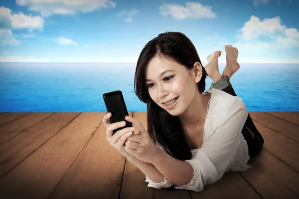 Flicka med hjälp av mobiltelefon på trägolv — Stockfoto