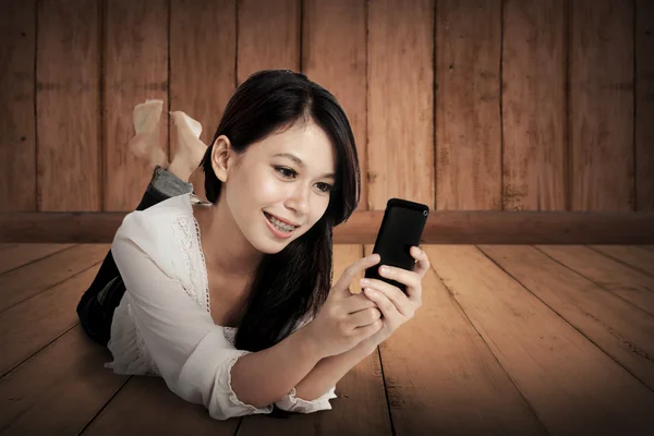 Fille à l'aide de téléphone portable sur le sol en bois — Photo