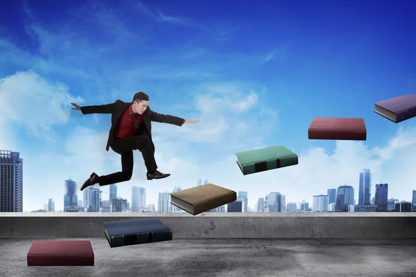 Geschäftsmann tritt fliegendes Buch in die Höhe, das wie eine Treppe aussieht — Stockfoto