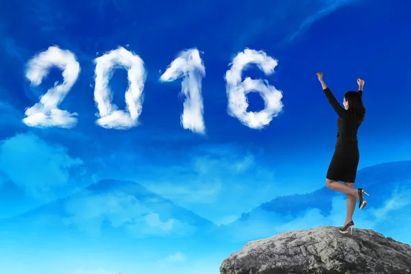 Business woman standing on the top of mountain, looking cloud shape 2016 number on the sky