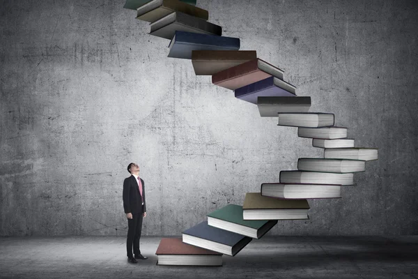 Biznes człowiek krok pływające pod książki, które wyglądają jak schodów — Zdjęcie stockowe