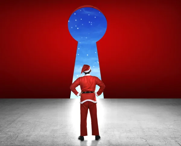 Homem vestindo traje de Papai Noel olhando grande buraco chave — Fotografia de Stock