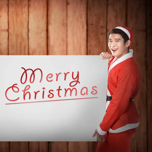 Mann im Weihnachtsmann-Kostüm hält Banner mit fröhlichen Weihnachtsliedern in der Hand — Stockfoto