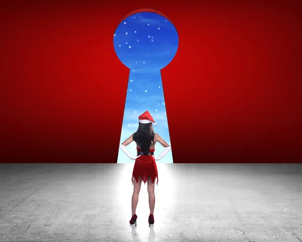 Frau im Weihnachtsmann-Kostüm sieht großes Schlüsselloch — Stockfoto