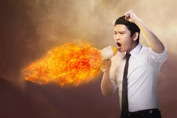 Businessman holding megaphone in fire and shouting — Stock Photo, Image