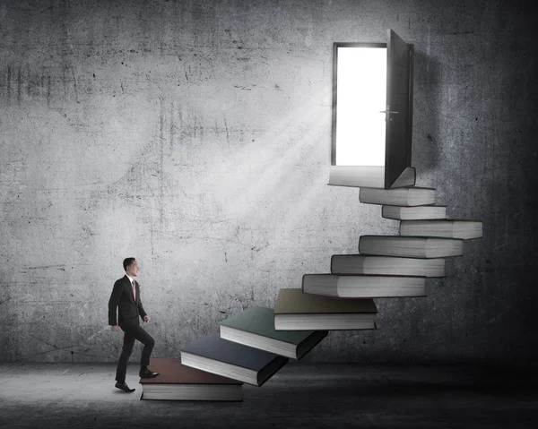 Hombre de negocios escalando escaleras hechas de libro —  Fotos de Stock