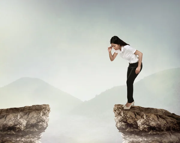 Business person looking down from cliff — Stock Photo, Image