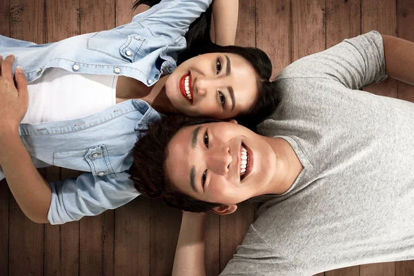 Lovely asian couple lying on the floor — Stock Photo, Image