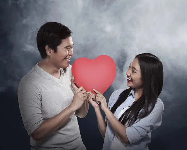 Encantador casal segurando coração vermelho — Fotografia de Stock