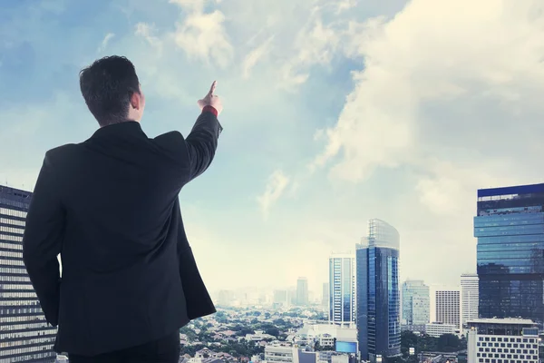 Asiatischer Geschäftsmann blickt vom Dach auf die Stadt — Stockfoto