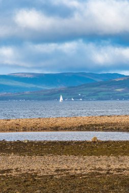 Clyde Firth 'te geçen Largs kasabasından İskoçya' nın batısındaki Rothesay ve Dunoon 'a, beyaz yelkenli bir yatın üzerinde dramatik bir kış gökyüzü ile..