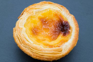 Koyu gri arka planda küçük bir kremalı tart..