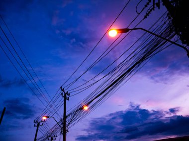Beautiful Purple and Blue Twilight Sky with Electric Power Lines and Street Lights Creating Dramatic Urban Silhouette