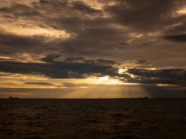 Dramatic Golden Sunset Over Ocean Sea with Heavy Storm Clouds and Ship Silhouette on Horizon - Epic Seascape Sky Background.