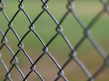 Close-Up of Chain Link Fence with Shallow Depth of Field - Metal Wire Mesh Barrier with Blurred Green Background