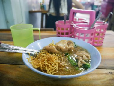 Crispy Fried Noodles with Wonton Dumplings in Thick Gravy Sauce - Traditional Chinese Thai Noodle Dish.