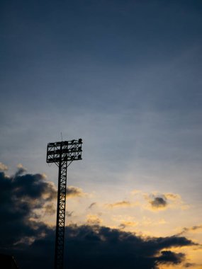 Stadyum Projektör Kulesi 'nin Silueti Gün batımına karşı Altın Bulutlu Gökyüzü Alacakaranlıkta