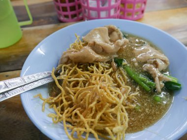Crispy Fried Noodles with Wonton Dumplings in Thick Gravy Sauce - Traditional Chinese Thai Noodle Dish.