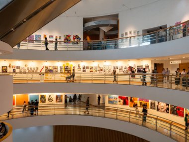 Ziyaretçiler, Bangkok Sanat ve Kültür Merkezi (BACC) bünyesindeki eğri kaldırımlar boyunca çağdaş sanat sergilerini görüyorlar. Toplantı yeri Bangkok, Tayland 'da büyük bir yaratıcı ve kültürel merkez olarak hizmet vermektedir..