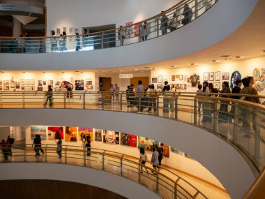 Ziyaretçiler, Bangkok Sanat ve Kültür Merkezi (BACC) bünyesindeki eğri kaldırımlar boyunca çağdaş sanat sergilerini görüyorlar. Toplantı yeri Bangkok, Tayland 'da büyük bir yaratıcı ve kültürel merkez olarak hizmet vermektedir..