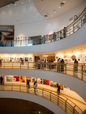 Ziyaretçiler, Bangkok Sanat ve Kültür Merkezi (BACC) bünyesindeki eğri kaldırımlar boyunca çağdaş sanat sergilerini görüyorlar. Toplantı yeri Bangkok, Tayland 'da büyük bir yaratıcı ve kültürel merkez olarak hizmet vermektedir..