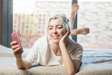 Onun yakın plan portresi. Hoş, tatlı, çekici, sevimli, sevimli, çekici, çekici, çekici, sarışın kadın. Yatakta uzanmış, erkek arkadaşıyla sohbet ediyor.