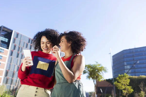 两名多种族年轻女子在城市里用手机玩乐的户外镜头 — 图库照片