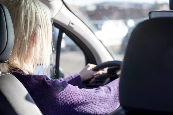 Kadın araba kullanırken ellerini direksiyona koyuyor.