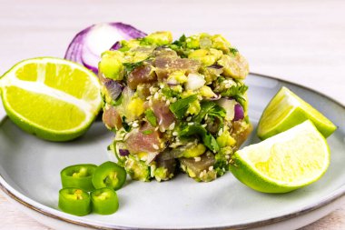 Avokado, limon, acı biber, kırmızı soğan, kişniş ve susam tohumlu deniz mahsullü ton balığı ceviche salatası beyaz ahşap arka planda. Kapatın. Seçici odaklanma. Boşluğu kopyala