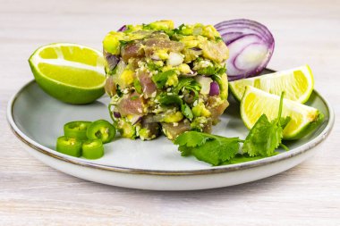 Avokado, limon, acı biber, kırmızı soğan, kişniş ve susam tohumlu deniz mahsullü ton balığı ceviche salatası beyaz ahşap arka planda. Kapatın. Seçici odaklanma. Boşluğu kopyala