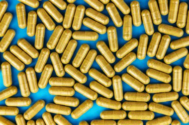 Mavi kağıtta haki sarısı haplar kapsülleri. Tam kare tıbbi konsept. Üst Manzara. Düz yatıyordu