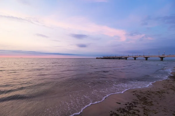 Kolobrzeg, Lengyelország-pier. Tenger a sunset parton fekvő — Stock Fotó