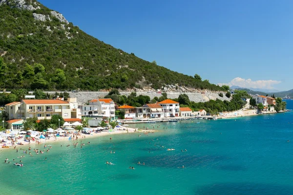 Belle eau bleue et la plage au pied des montagnes, station de vacances — Photo