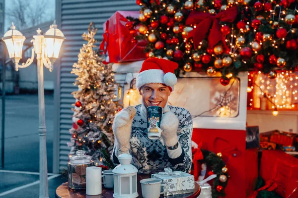 Młody Chłopiec Jako Święty Mikołaj Pijący Kawę Pobliżu Świątecznego Autobusu — Zdjęcie stockowe