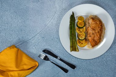 Kahverengi pirinç yatağında pişmiş tavuk göğsü. Yanında da kabak ve kuşkonmaz.. 